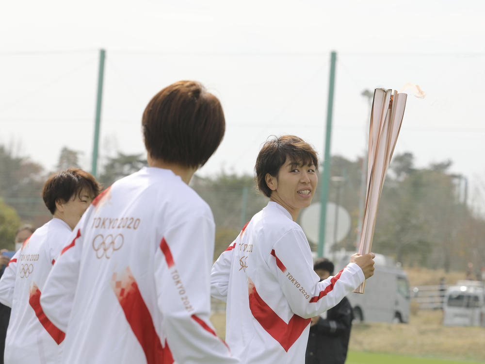 Azusa Iwashimizu (right) and other members of Japan women's national football team run as torchbearers in the first leg of the torch relay for Tokyo Olympics on Thursday in Fukushima prefecture, Japan.
