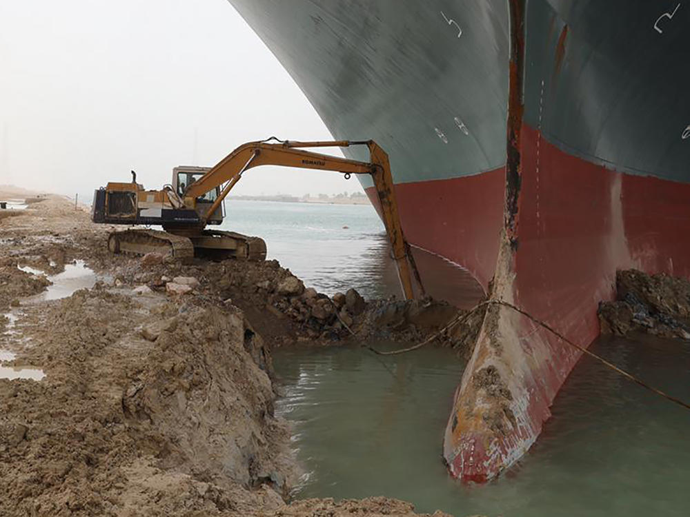 Heavy equipment is used to try to dig out the keel of the Ever Given, a massive cargo ship wedged across the Suez Canal.