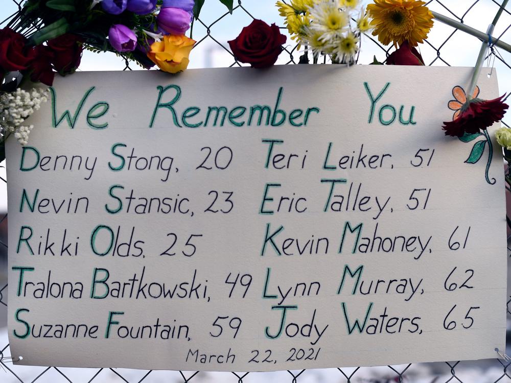 A sign framed with flowers lists victims' names on a fence outside a King Soopers grocery store in Boulder, Colo. The suspect in the mass shooting made his first court appearance on Thursday.