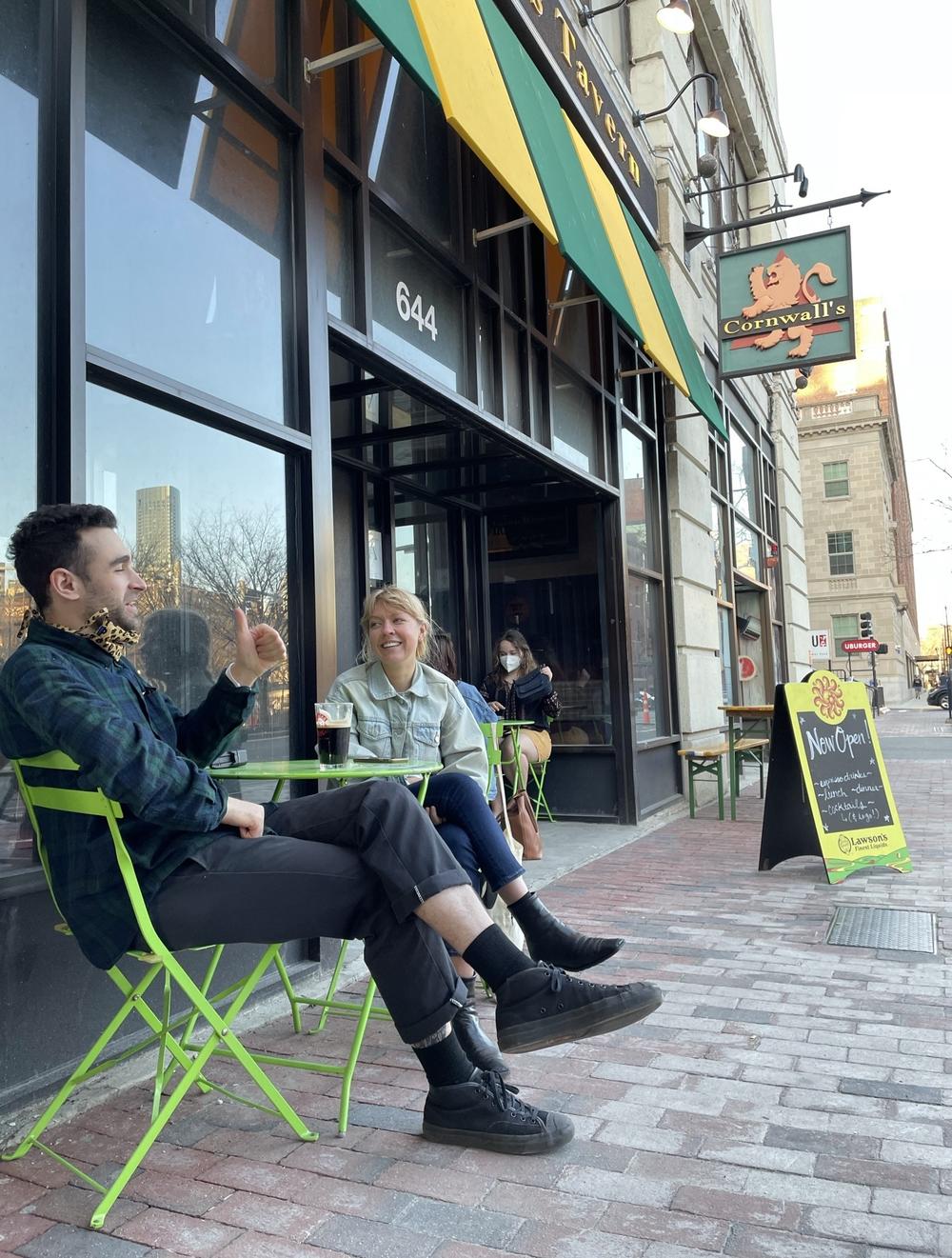 Grad students Julian Geltman and Kailey Slavik savor a cold beer and the warm weather on the first day that Boston restaurants are allowed to put tables out on the sidewalks again, and Cornwall's delights in the extra business.