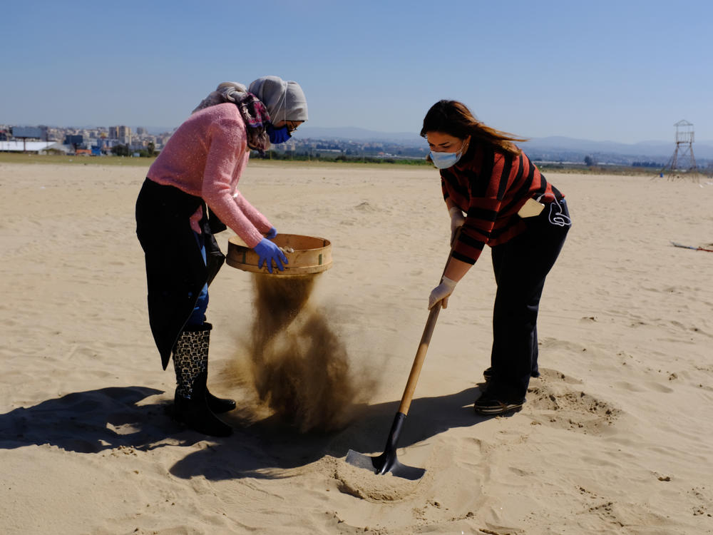 Marine biology student Ranim Tahhan, 21, pictured left, and another volunteer work to clean Tyre beach from the pollution caused by an oil spill in the eastern Mediterranean Sea.
