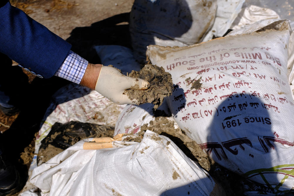 Hassan Dbouk points to bags filled with tar collected by volunteers from Tyre nature reserve beach.
