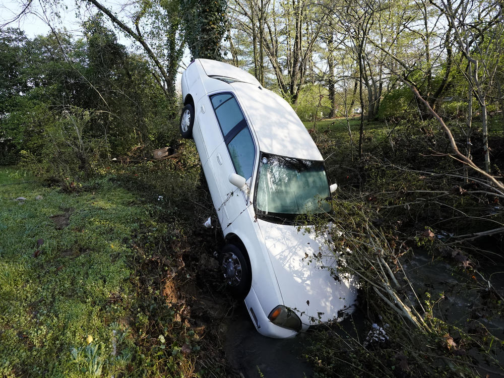 A car that was carried by floodwaters leans against a tree in a creek in Nashville, Tenn., on Sunday. Heavy rainfall flooded roads, submerged vehicles and left many people in need of rescue.