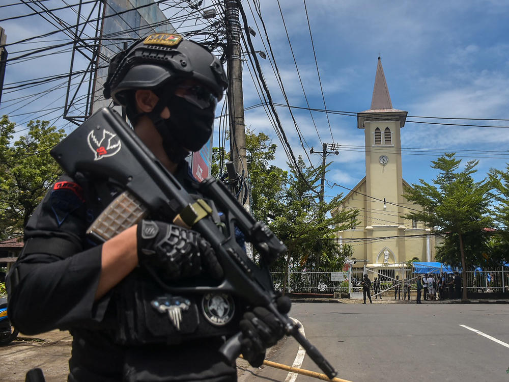 A police officer stands guard outside the Sacred Heart of Jesus Cathedral in Makassar, Indonesia, on Sunday. Two suicide bombers attacked the Roman Catholic compound, injuring at least 20 people.