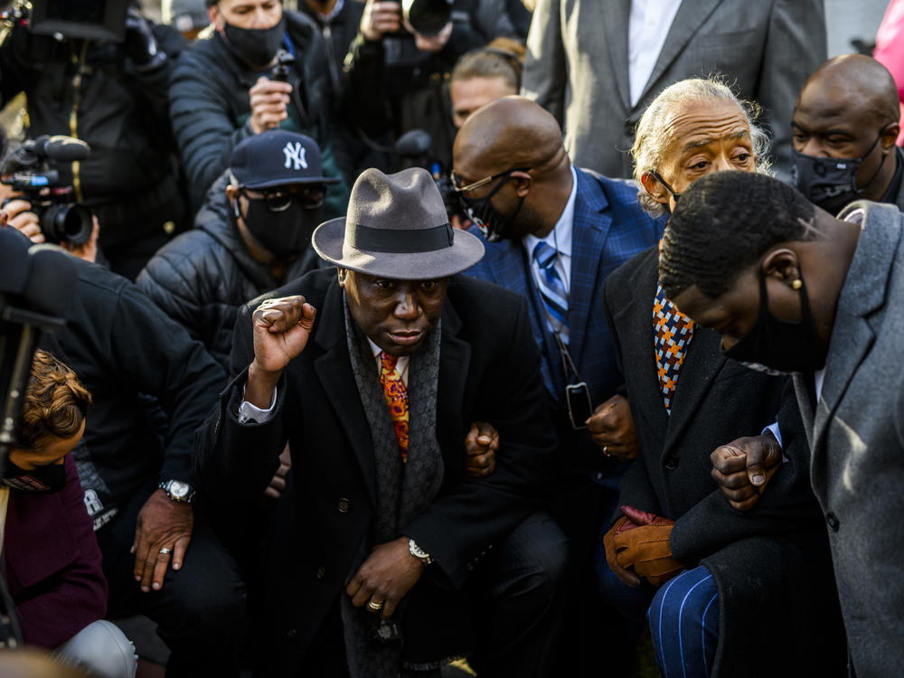 Attorney Ben Crump (center) took a knee with members of George Floyd's family and Rev. Al Sharpton for 8 minutes and 46 seconds outside the Hennepin County Government Center in Minneapolis, Minn., on Monday, shortly before opening arguments began in the trial of former police officer Derek Chauvin.