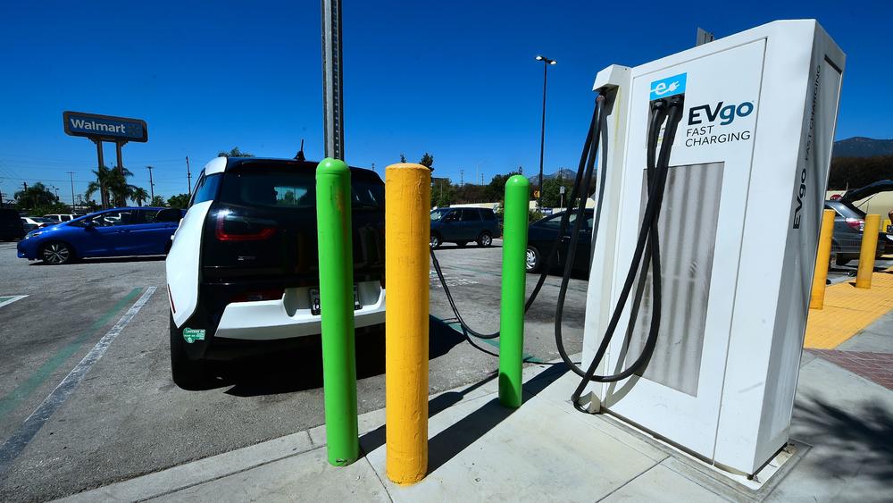 An electric vehicle is plugged in for a charge at stations in a Walmart parking lot in Duarte, Calif. Biden is proposing $174 billion in spending on boosting the electric vehicle market.