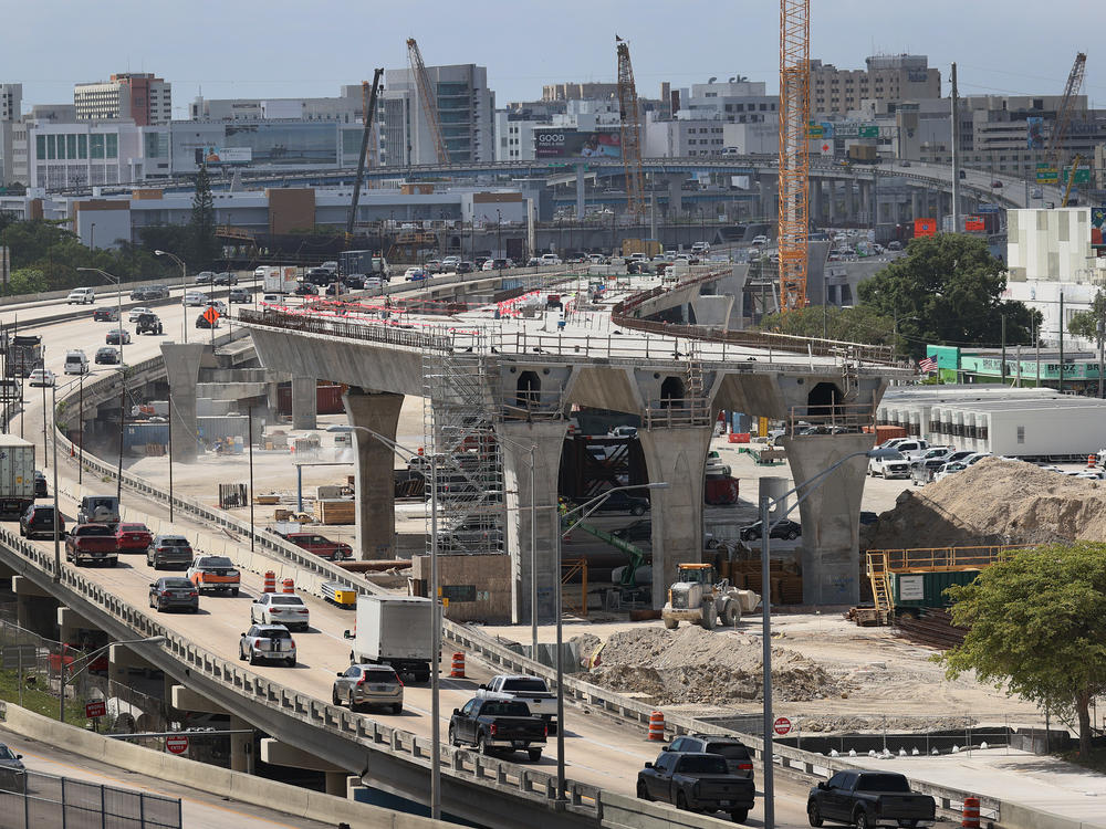 Workers improve a busy highway intersection in Miami. President Biden is proposing roughly $2 trillion to invest in the nation's infrastructure. His plan includes improvements for roads, bridges, transit, water systems, electric grids and Internet access.