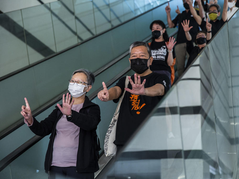 Former lawmaker Cyd Ho (left) and pro-democracy activist Lee Cheuk-yan (center) gesture a protest slogan, 