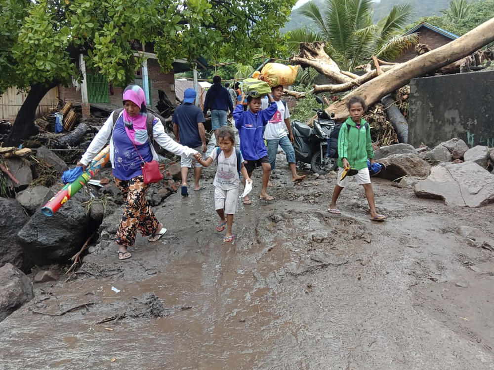 People walk amid debris Sunday in a village affected by flooding in Ile Ape on Lembata Island in Indonesia's East Nusa Tenggara province.
