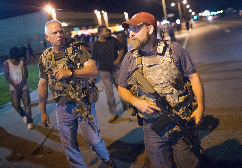 Reported members of the Oath Keepers walk along West Florissant Street as demonstrators mark the anniversary of the shooting of Michael Brown in August 2015 in Ferguson, Mo.