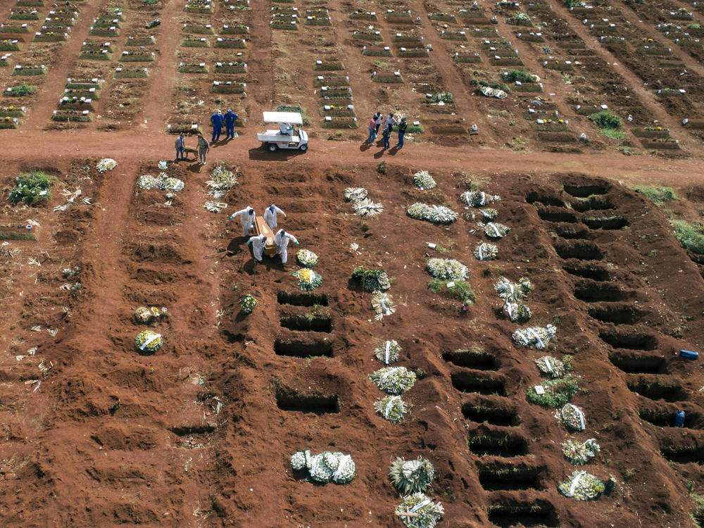 Cemetery workers wearing protective gear carry the coffin of a person who died from complications related to COVID-19 to a gravesite at the Vila Formosa cemetery in Sao Paulo, Brazil, Wednesday, April 7, 2021.