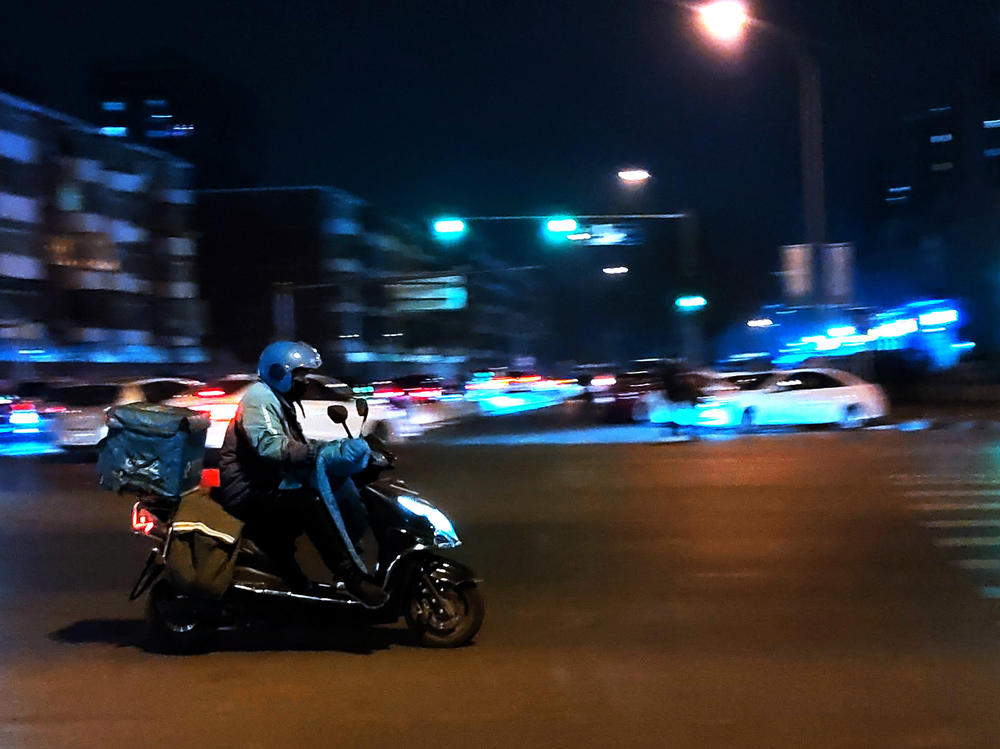 A courier delivers goods at night on a street in Beijing in February.