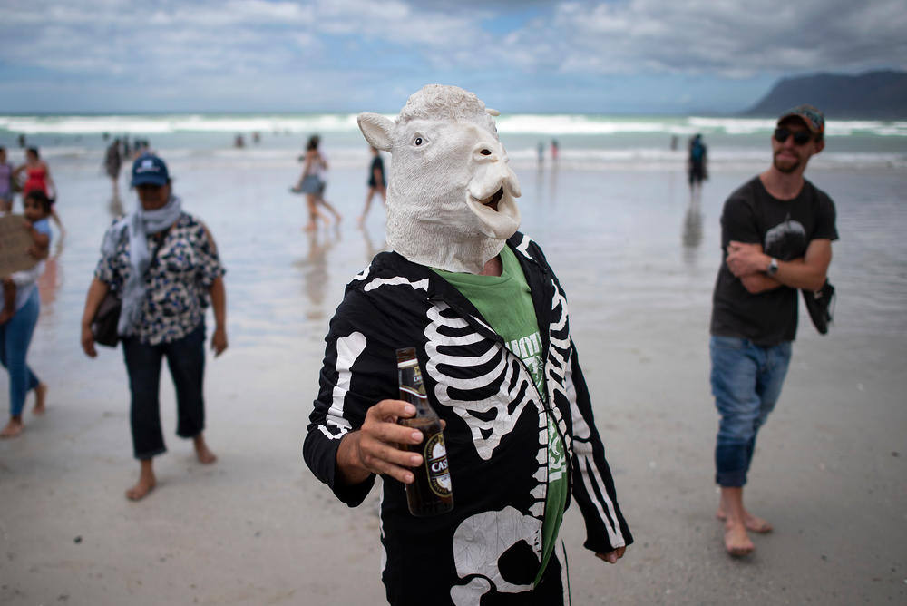 A costumed man takes a stand. He's enjoying the beach with an alcohol-free beer in Cape Town's Muizenberg district in January, when South Africa's ban on beach gatherings and booze was still in effect. The measures were intended to prevent the spread of COVID-19.