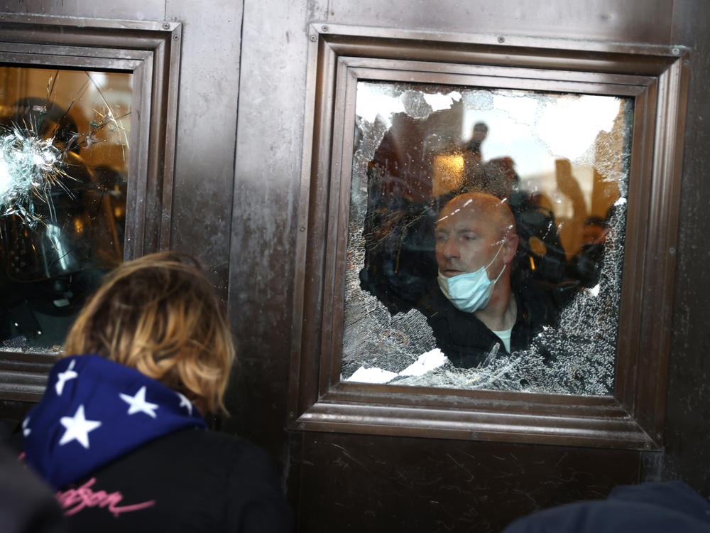 A Capitol police officer looks out of a broken window as pro-Trump rioters storm into the building on Jan. 6.