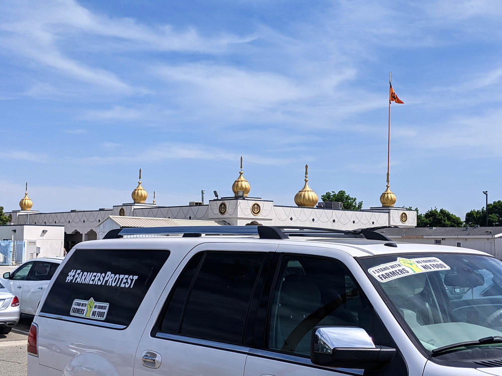 A car parked in a Fresno Gurdwara, or Sikh temple, parking lot with a bumper sticker showing support for Indian farmers protesting new agricultural laws.