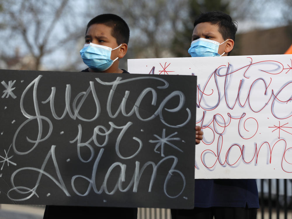 Two boys hold signs at an April 6 news conference, days after a Chicago police officer fatally shot 13-year-old Adam Toledo.