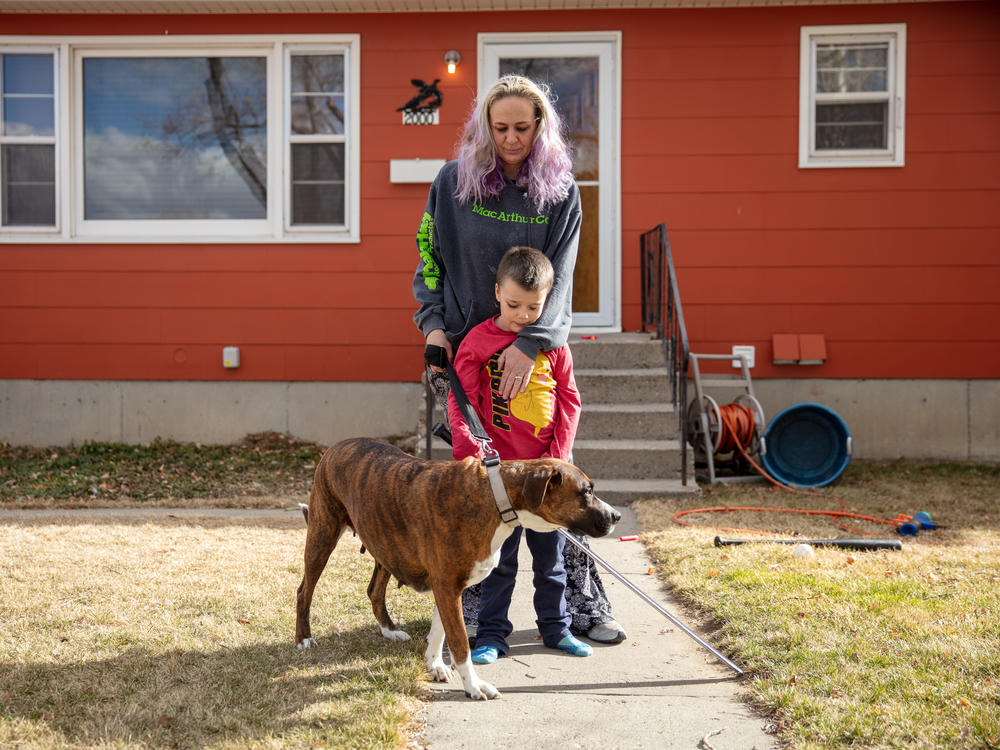 Barbara Gaught stands outside the home she's now renting in Billings, Mont., with her 5-year-old son, Blazen, and their dog, Arie. Gaught and her family were evicted from the mobile home they had owned outright and lived in for 16 years because they fell behind on 'lot rent' for the little plot of land under the mobile home.