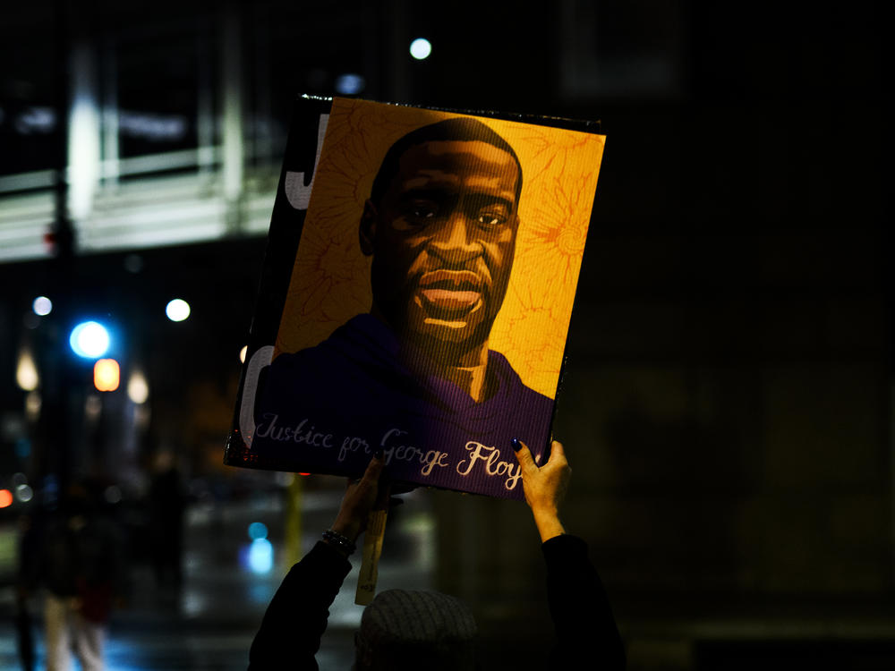 A person holds up a portrait of George Floyd as people gather outside the Hennepin County Government Center on April 9 in Minneapolis