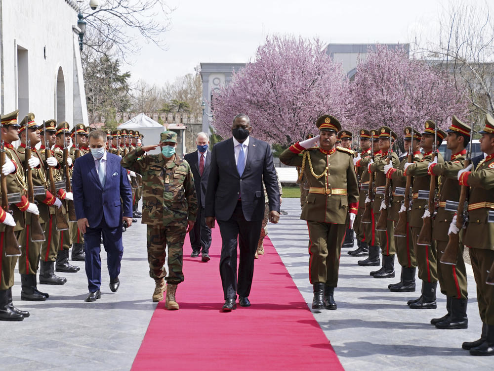 U.S. Defense Secretary Lloyd Austin, center, walks on the red carpet with Afghan officials as they review an honor guard at the presidential palace in Kabul, Afghanistan, on March 21. President Biden said the U.S. will withdraw all remaining troops from the country by Sept. 11, ending the U.S. involvement in the America's longest-ever war.