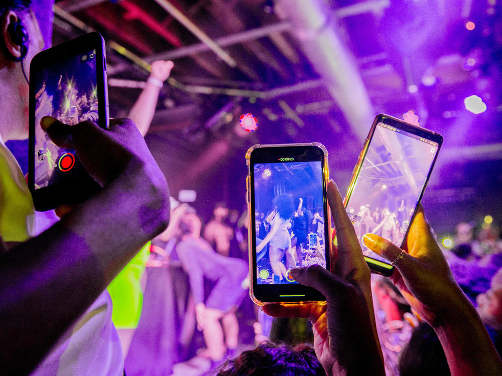You can do a lot of things with minimal risk after being vaccinated. Although our public health expert says that maybe it's not quite time for a rave or other tightly packed events. Above: Fans take photographs of Megan Thee Stallion at a London show in 2019.