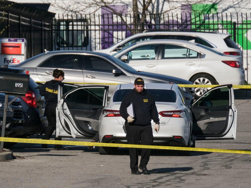 Crime scene investigators walk through the parking lot of a FedEx facility in Indianapolis on Friday. A gunman killed at least eight people and injured several others.