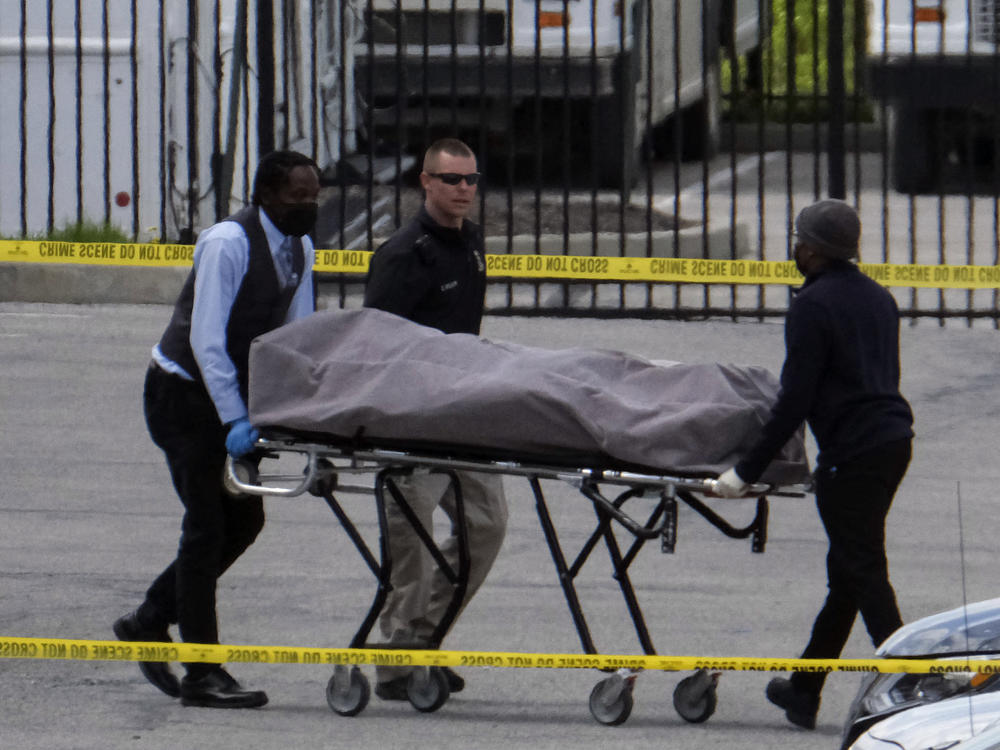 Officials recover a body Friday at the site of a mass shooting at a FedEx facility in Indianapolis.