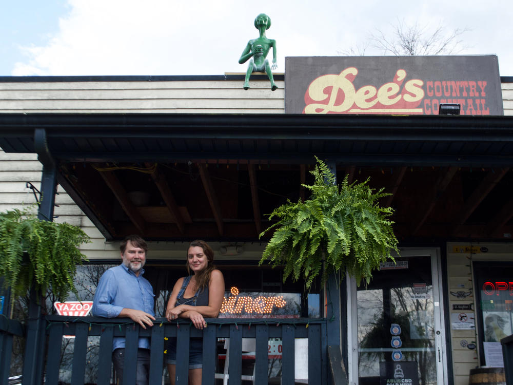 Daniel Walker and Amy Dee Richardson, owners of Dee's Country Cocktail Lounge pose with the alien on their roof, Rick.
