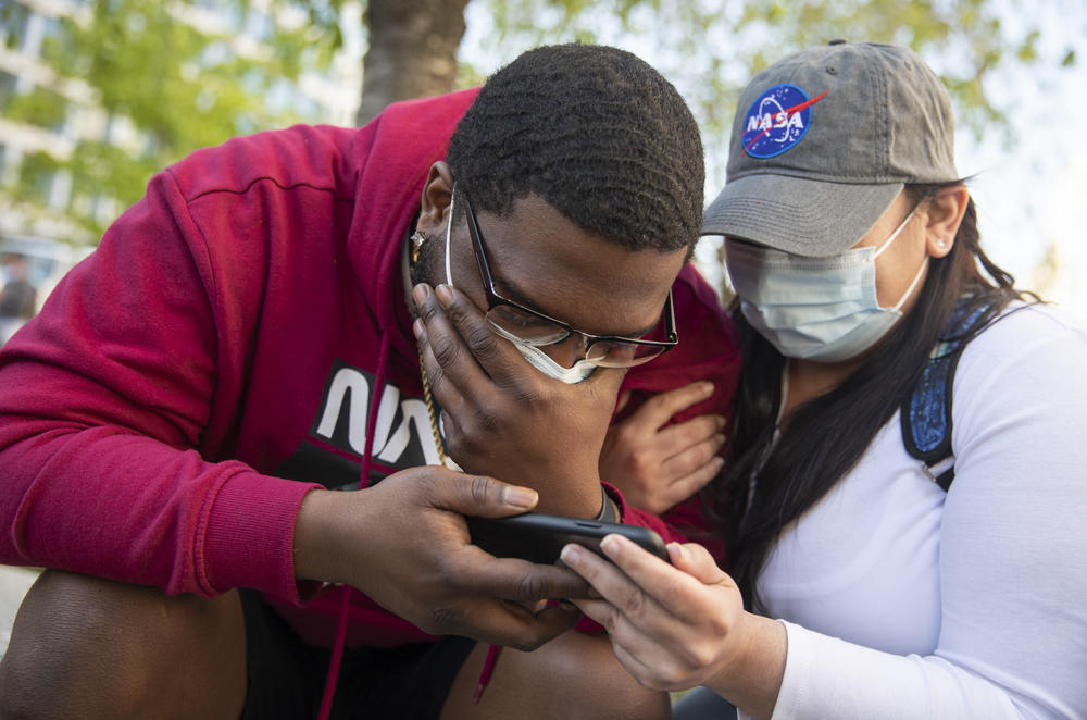 London Williams, left, and Stephanie Toledo react to the verdict. They are from Harrisburg, Pa., and were in Washington on a date. They were walking by Black Lives Matter Plaza when they saw the crowd and journalists and found out the verdict was about to come down and stopped to watch on a cellphone.