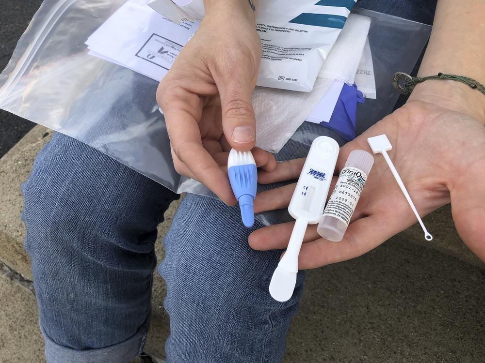 Brooke Parker, an organizer with the group Solutions Oriented Addiction Response, displays an HIV testing kit in Charleston, W.Va., in March. Outbreaks of HIV/AIDS are expected to rise as resources have been redirected to the fight against COVID-19 — delaying and sometimes cutting off HIV testing and treatment.