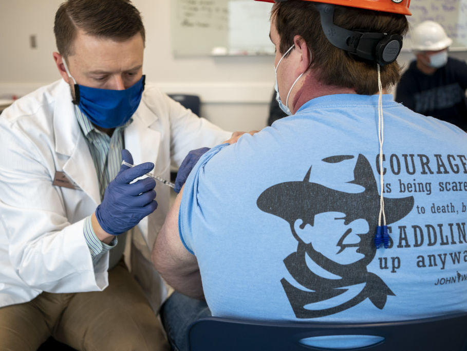 A pharmacist administers a dose of a COVID-19 vaccine to a worker at a processing plant in Arkansas City, Kan., on March 5. Researchers are concerned that vaccination rates in some rural communities may not keep up with urban rates.