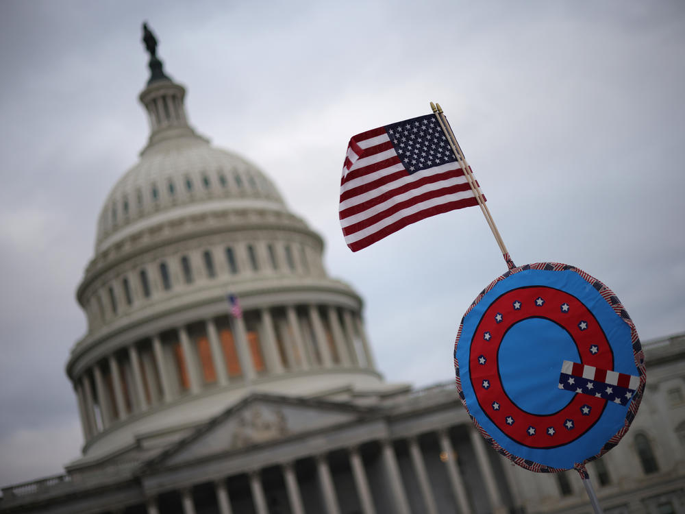 Supporters of then-President Donald Trump fly a U.S. flag with a symbol from the QAnon conspiracy theory as they gather outside the Capitol on Jan. 6 ahead of the insurrection.