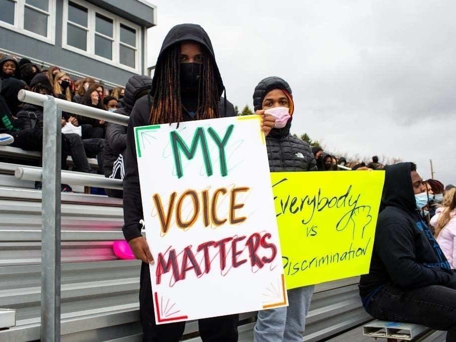Students hold signs during a walkout at Tartan High School in Oakdale, Minn., where participants spoke, sang and did trauma-healing exercises together on the football field Monday.