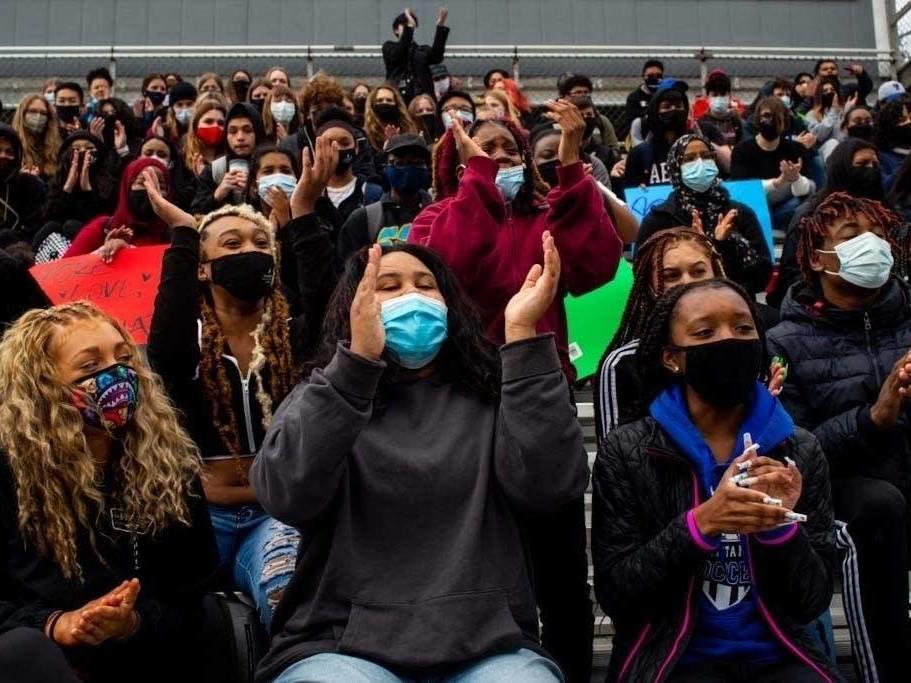 Students cheer after Jalen Silas-Burch performed a spoken-word piece during a walkout at Tartan High School in Oakdale, Minn., where participants spoke, sang and did trauma-healing exercises together on the football field on Monday.