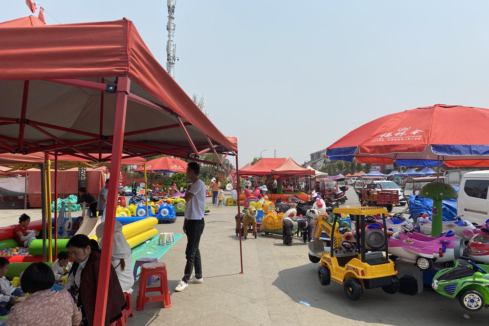 Luo Beiling relocated from a remote village to Qixingguan and now works in this market outside the compound.