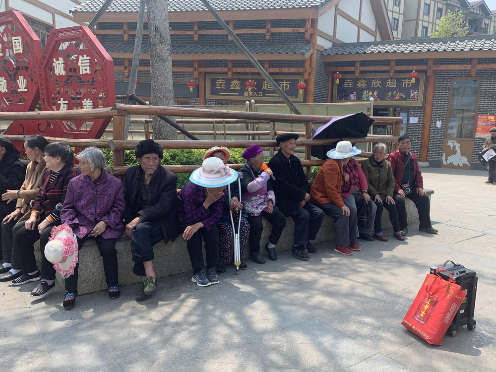 Resettled villagers sun themselves outside Qixingguan. Many older residents have had a difficult time adjusting to life away from their fields.