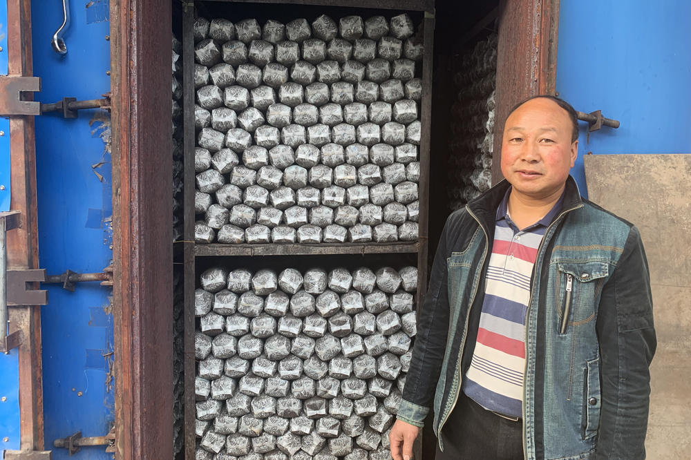 Sun Dahui, a mushroom co-op manager, stands outside a self-made oven, which heats logs of mushroom-growing medium. The cooperative hopes to expand into making mushroom-based sauces soon.