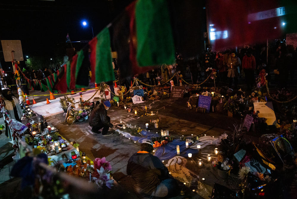 People lay candles on a painting of an angel where George Floyd was killed.