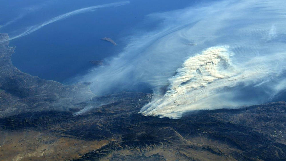 This 2017 photo from the International Space Station shows smoke from wildfires in Ventura County, Calif. The increasing human and economic toll of extreme weather events will underscore the urgency of President Biden's message at a global summit focused on reducing carbon emissions.