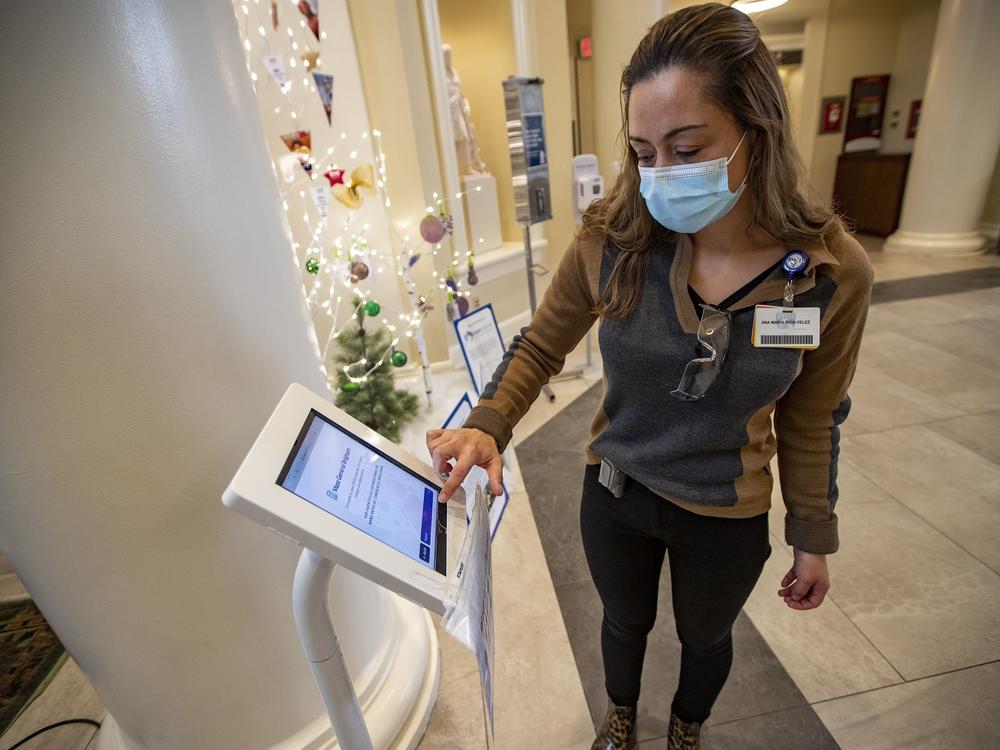 Interpreter Ana Maria Rios-Velez demonstrates the screening app at the front entrance of Brigham and Womens Hospital in Boston. It has a multilingual function to better communicate with non-English speaking patients and staff.