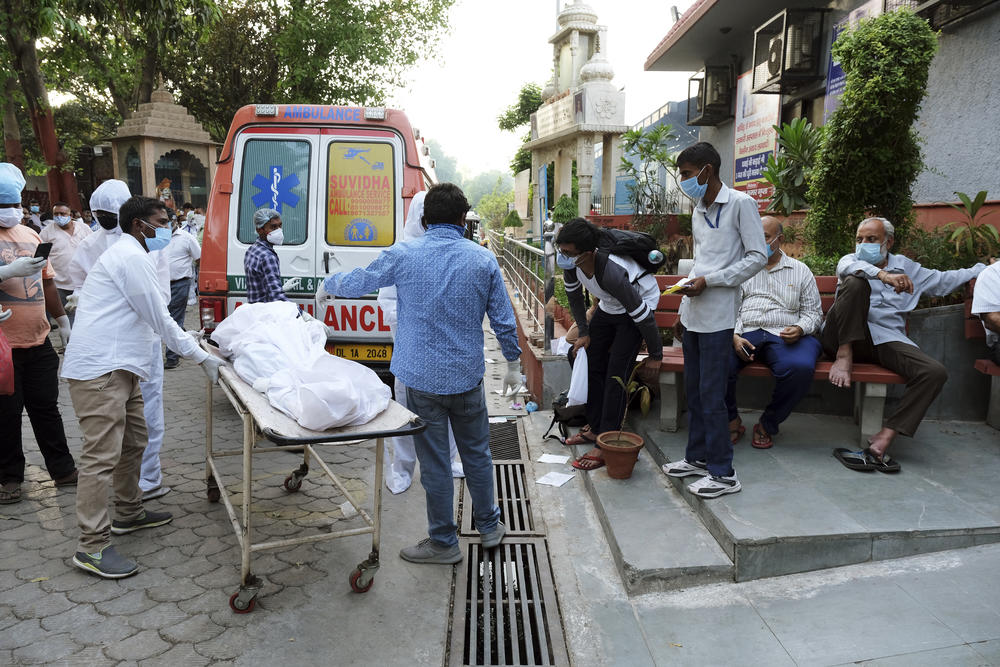 Relatives carry the shrouded body of a family member, who died of COVID-19, from an ambulance to a crematorium this week in New Delhi.