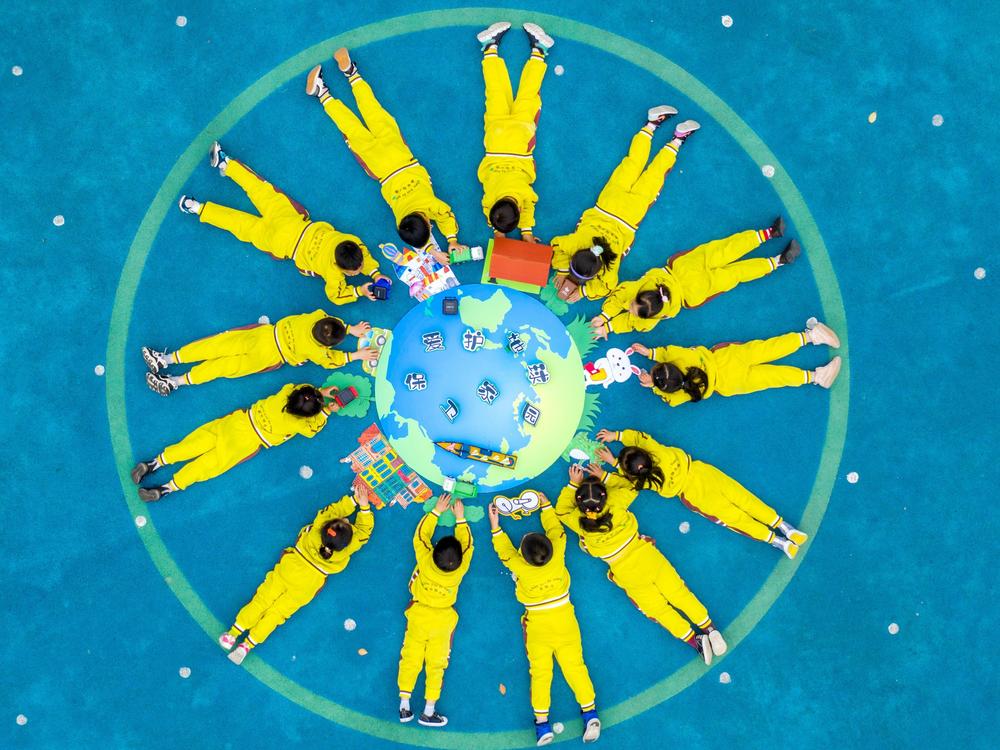 Children make an image of the Earth with green materials at a kindergarten on the 52nd Earth Day on April 22 in Changxing County, Zhejiang Province of China.
