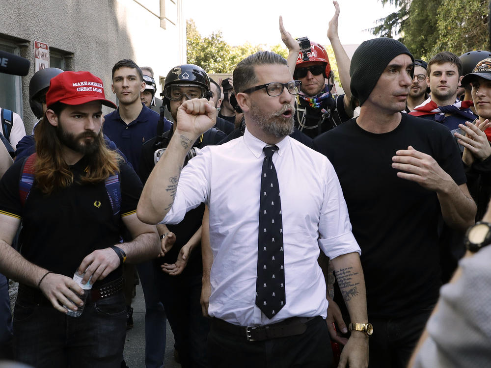 In this 2017 photo, Gavin McInnes (center), founder of the far-right extremist group known as the Proud Boys, is surrounded by supporters after speaking at a rally in Berkeley, Calif. McInnes told NPR that the group is made up of 
