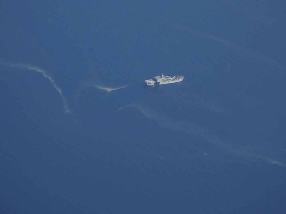 An Indonesian navy ship works near what appears to be oil slicks during a search Friday for the submarine KRI Nanggala 402 in the Bali Sea.