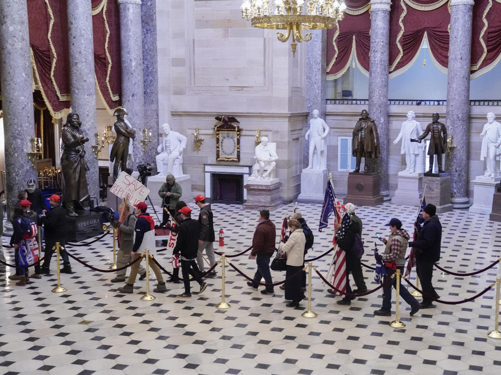 Supporters of then-President Donald Trump walk through Statuary Hall of the U.S. Capitol on Jan. 6. A New York man was arrested Thursday after allegedly boasting on a dating app he had stormed the Capitol and 