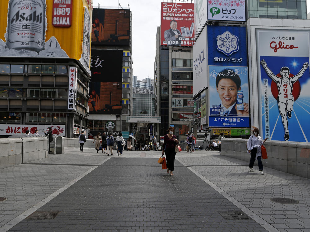 Japan on Friday announced a third state of emergency over the COVID-19 pandemic with new restrictions taking effect Sunday. Here, a woman walks on a quiet Dotonbori Street. The arcade is normally one of Osaka's most popular tourist areas.