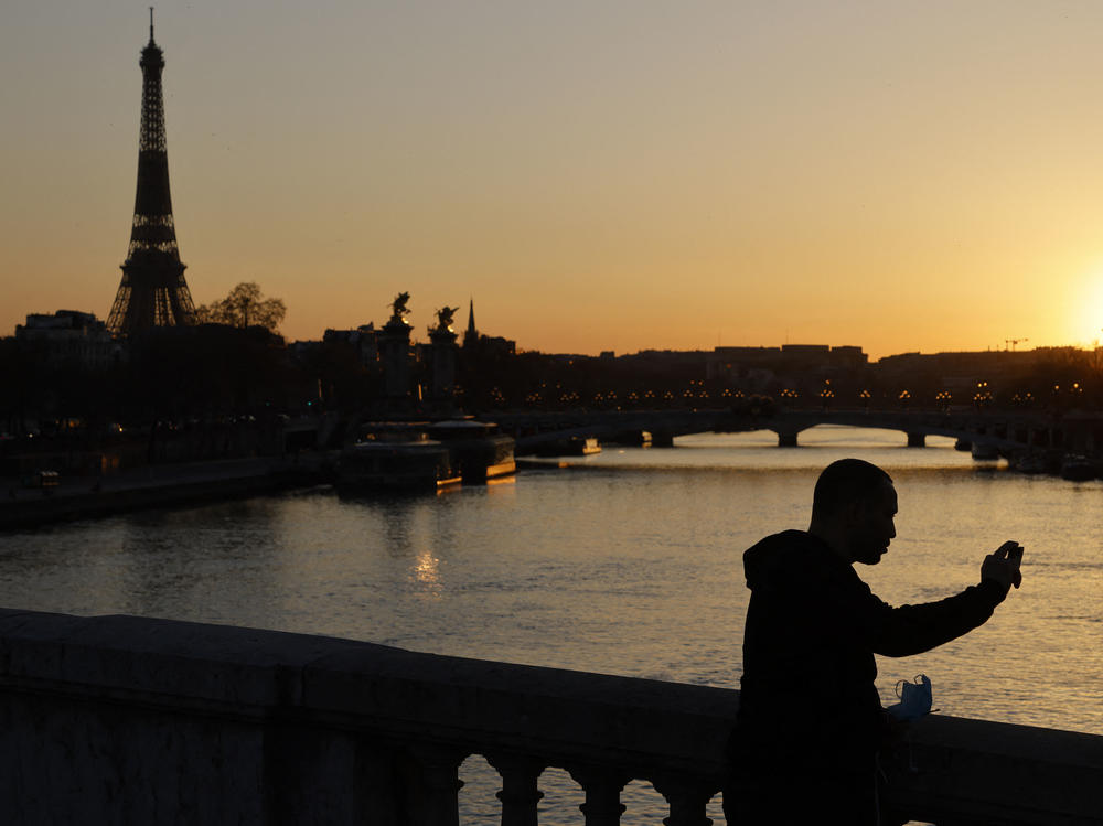 A man takes a picture at sunset with the Eiffel Tower in the background in March in Paris. The president of the European Commission says fully vaccinated Americans will be able to visit the European Union this summer.