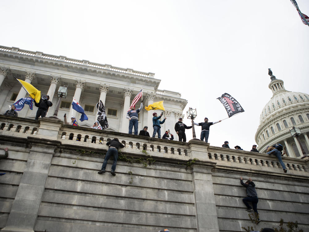 Supporters of former President Donald Trump climb the west wall of the the U.S. Capitol on Jan. 6. A New York man who was not at the riot is on trial for allegedly threatening to kill members of Congress in media posts supportive of the assault.