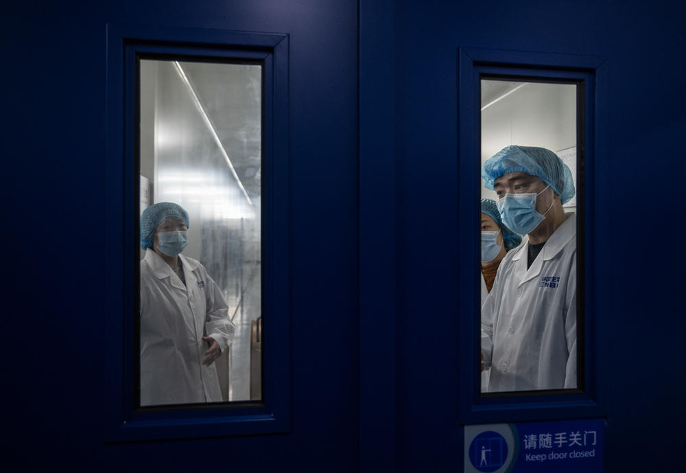 Workers wait to open a secure door in the packaging area of Sinopharm's COVID-19 vaccine during a media tour organized by the State Council Information Office in February in Beijing. Sinopharm is one of China's largest state-owned biotech companies.