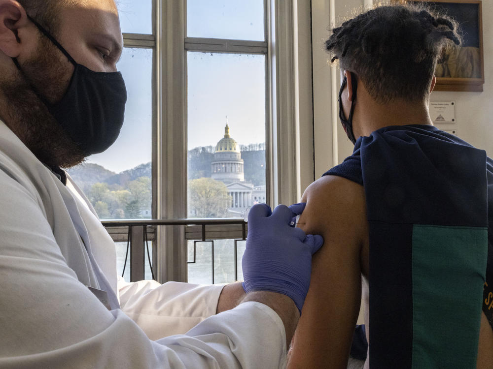 A young man receives a COVID-19 vaccine in Charleston earlier this month while overlooking the West Virginia Capitol building.
