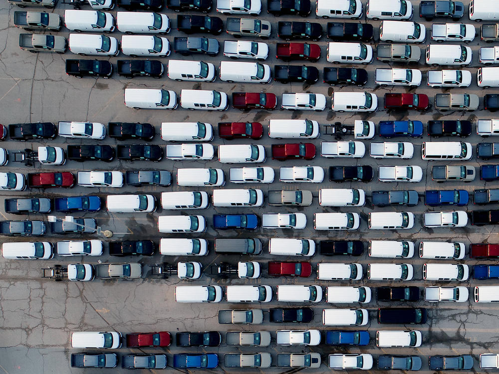 In this aerial photo, pickup trucks and vans are seen last month in a parking lot outside a General Motors assembly plant where they are produced in Wentzville, Mo. A key component in the car industry is in short supply: computer chips. Taiwan's chipmakers are racing to meet demand.